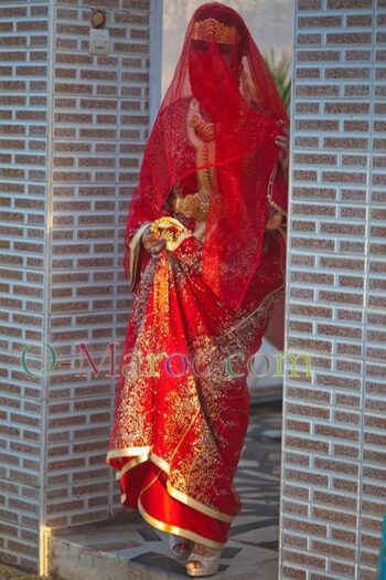 A bride in a red caftan descends a staircase