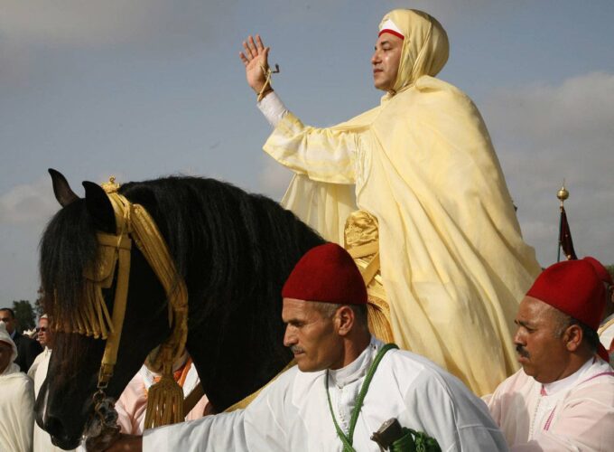 Dressed in yellow, the king rides on a horse amidst dignitaries on foot, dressed in white.