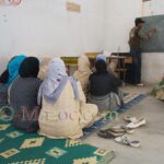Women sitting on the floor learning to read and write Arabic