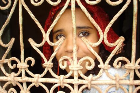 A young girl from Skoura, behind the latticework of a window