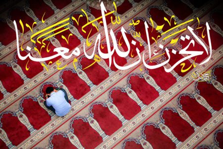 A man praying on a rug with religious calligraphy