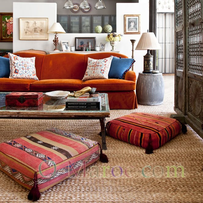 Coin salon avec un canapé, une table basse et deux grands coussins marocains. 
