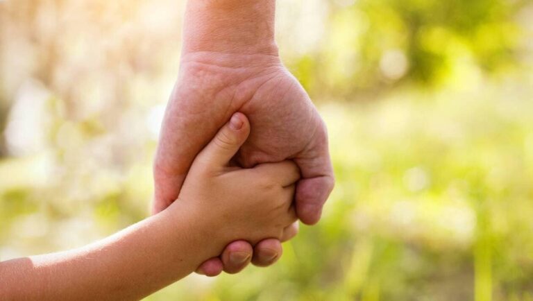 Hand of a child in the hand of an adult