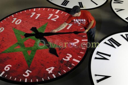 A man moves the hands of a clock decorated with the Moroccan flag