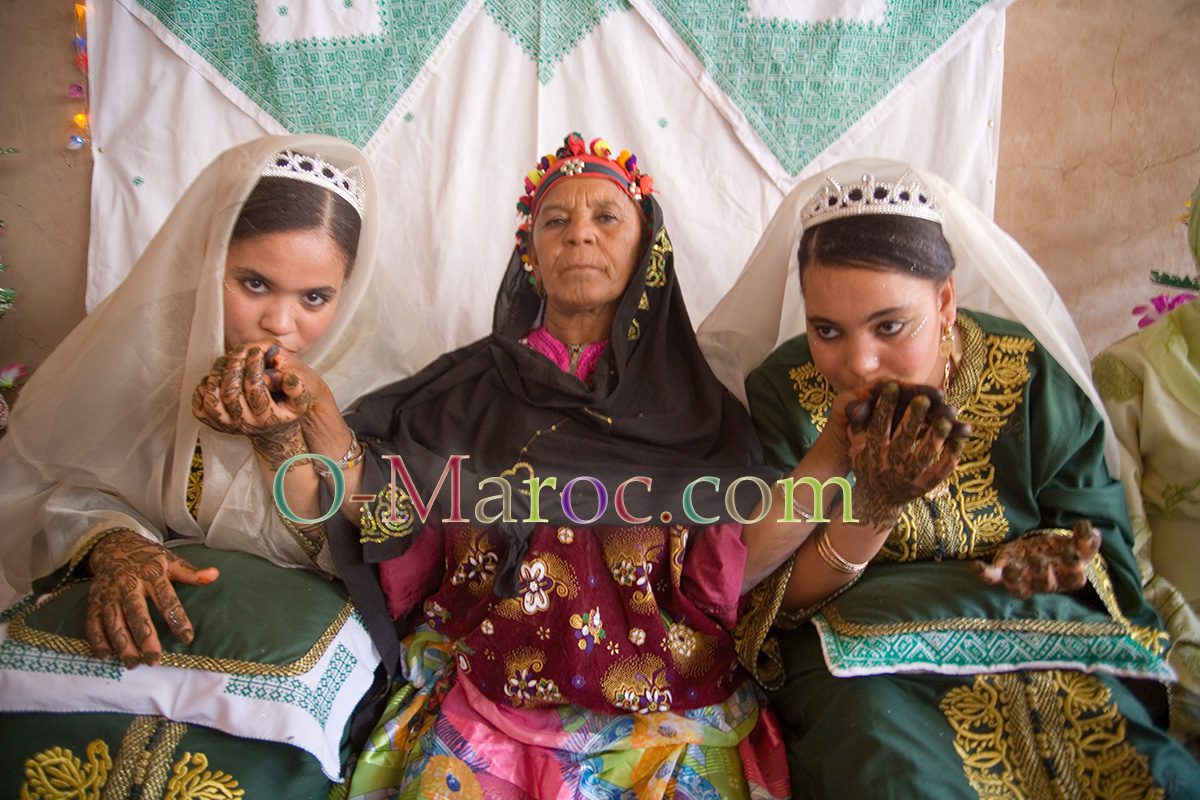 Two young brides pose for a photo kissing their grandmother's hand