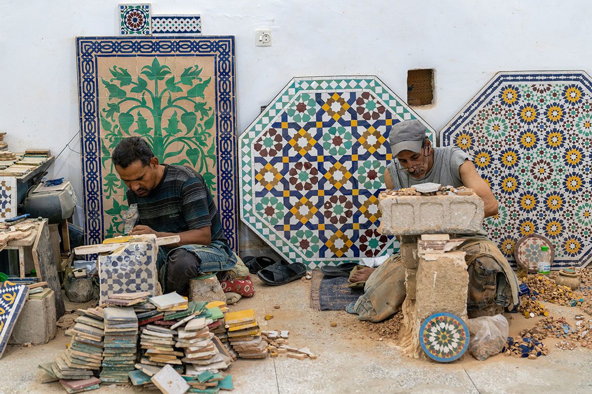 Two people prepare the ceramic blocks to make the zellij patterns