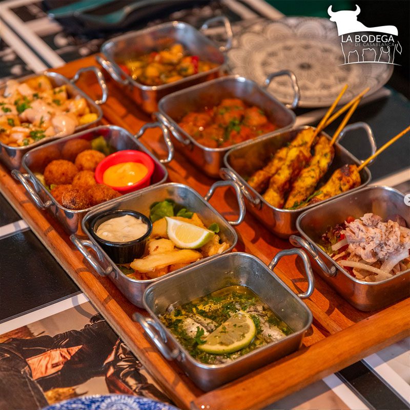 Assorted tapas in small metal dishes, by La bodega