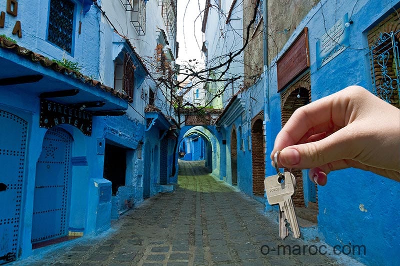 Hand giving keys against a background of the medina of Chefchaouen