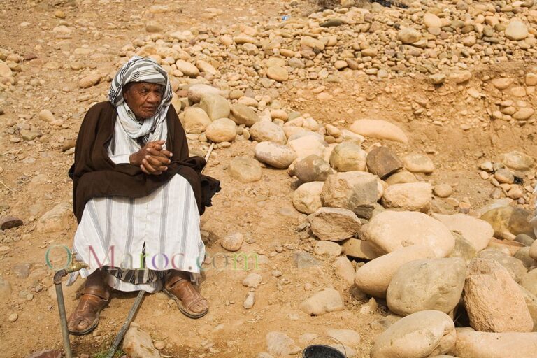 On a stone hill, an old man in djellabah